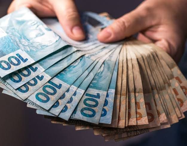 Notas de real nas mãos representando a declaração de imposto de renda do motorista de Uber